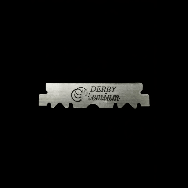 A single metal razor blade with 'Derby Premium' branding on it with a black background.
