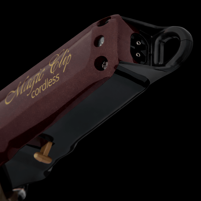 Close-up of a red and black electric clipper with 'Magic Clip cordless' branding on a dark background.