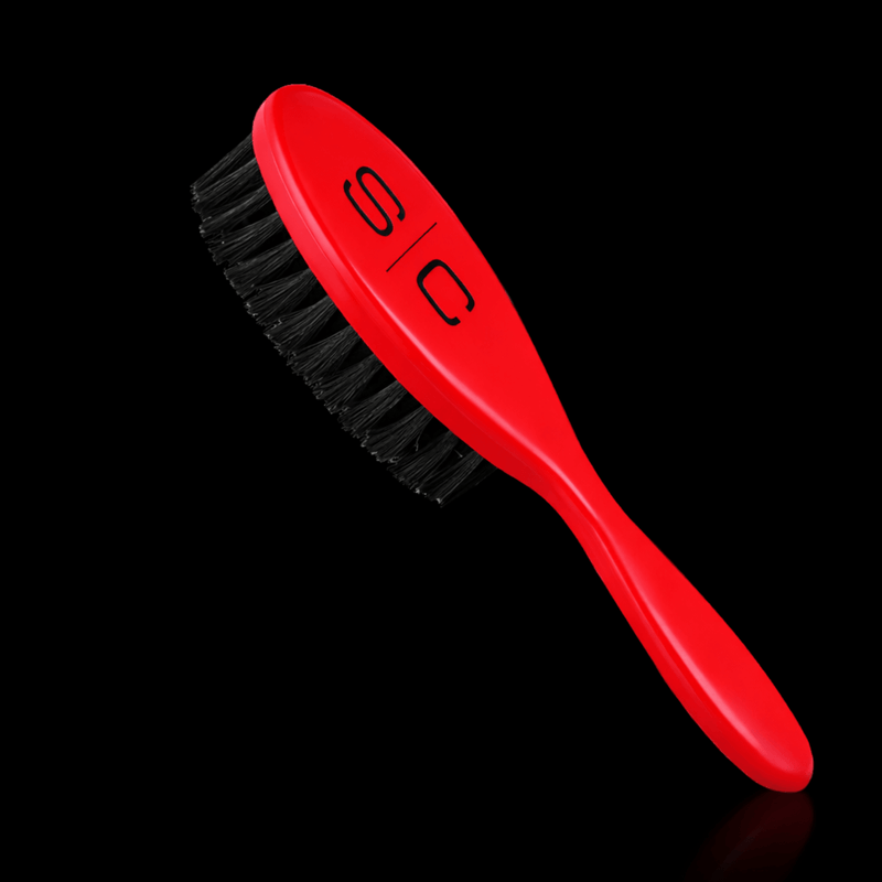 Red Stylecraft brush with black bristles on a black background angled Primos Barber Supply