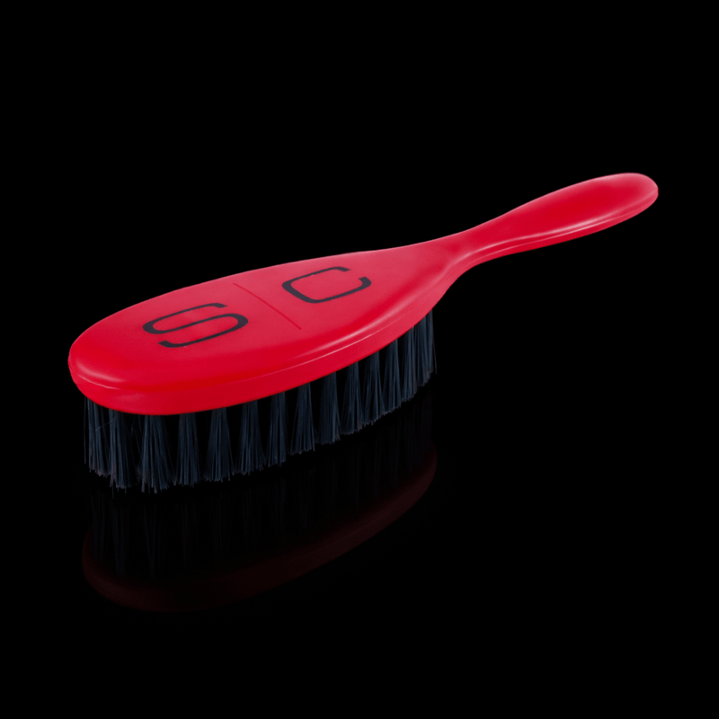 Red Stylecraft brush with black bristles on a black background Primos Barber Supply