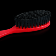 Red Stylecraft brush with black bristles on a black background zoomed Primos Barber Supply