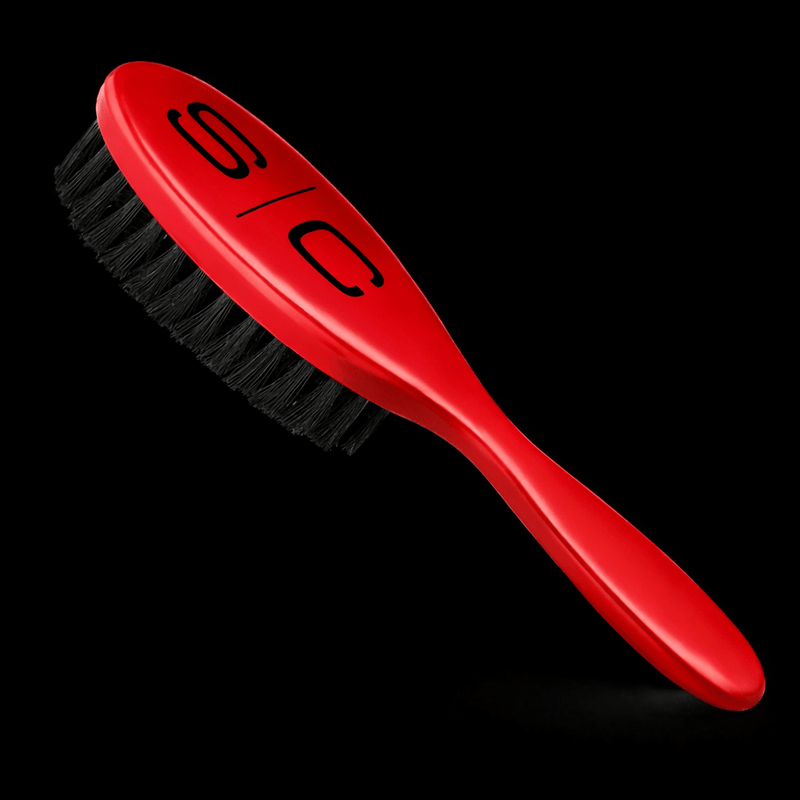 Red brush with black bristles on a black background