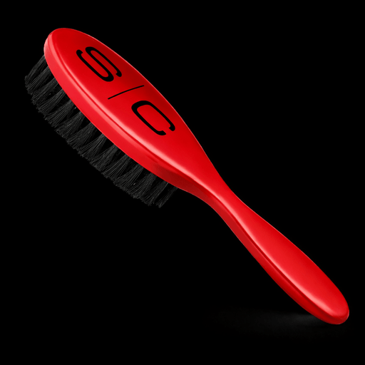 Red brush with black bristles on a black background