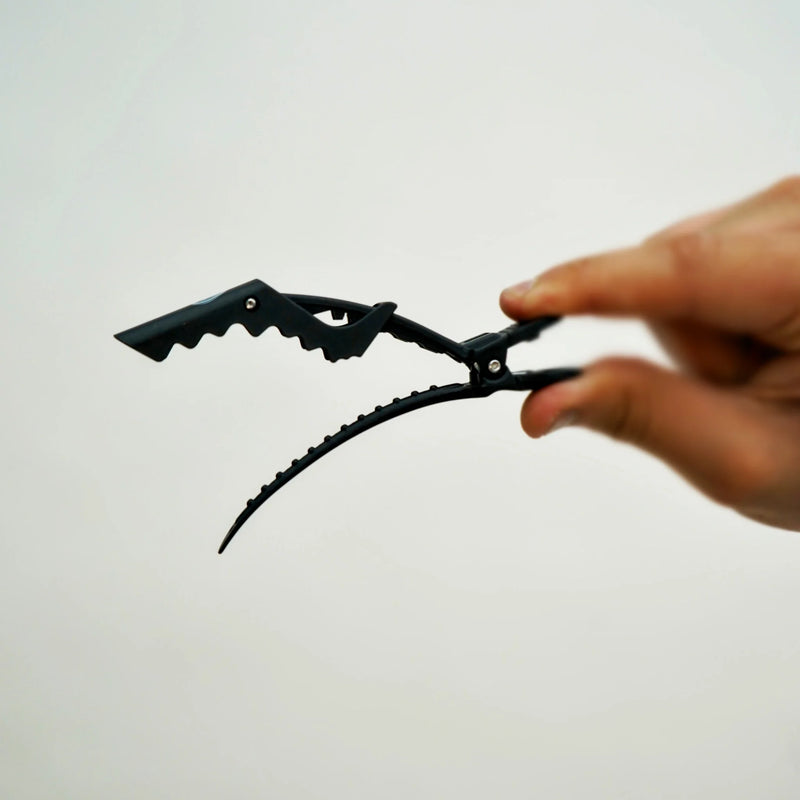 Hand holding a black metal tool against a light gray background