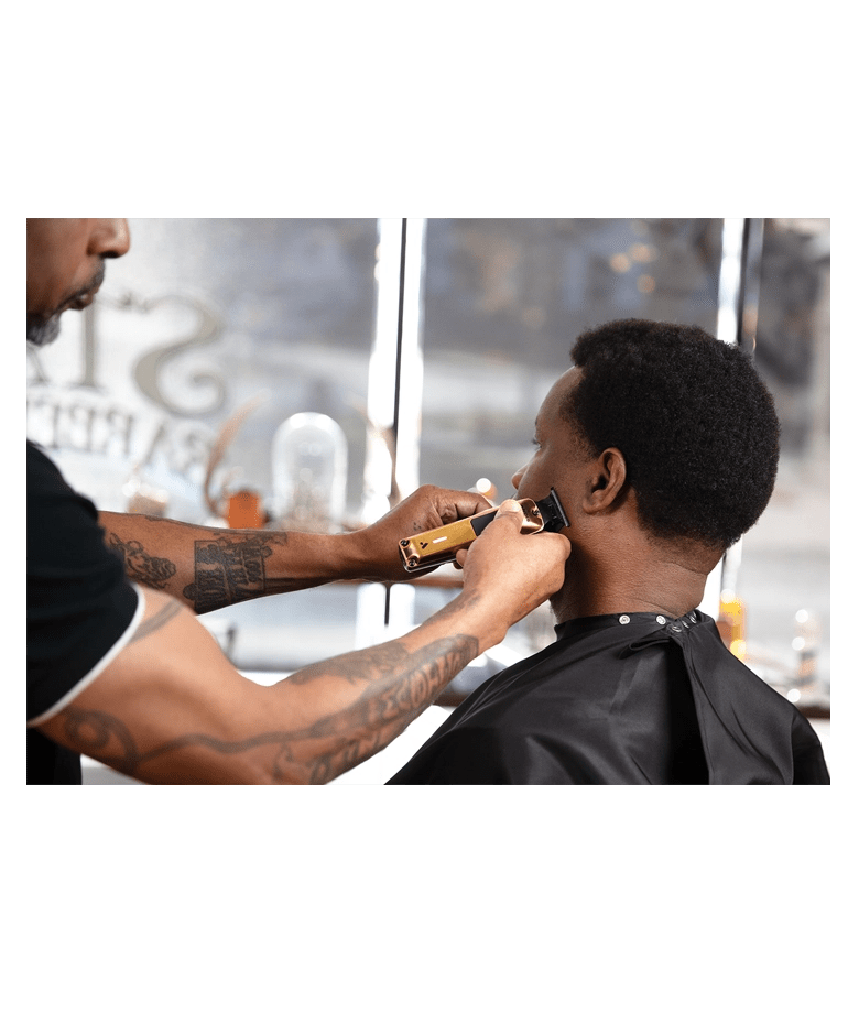 Barber using clippers on a customer's head in a salon setting.