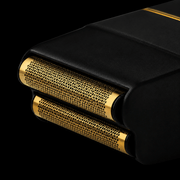 Close-up of a black and gold electric shaver on a black background