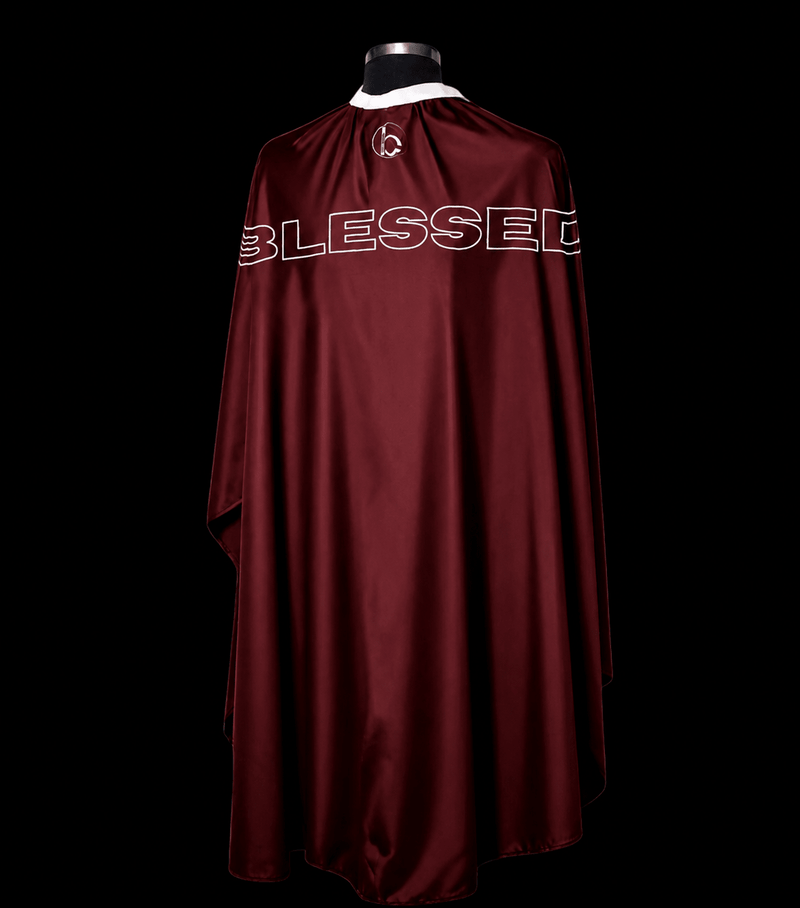 Blessed Capes Bordeaux barber cape in a solid maroon color featuring lightweight water-resistant material and full professional coverage for barbers and stylists.
