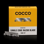 Cocco single edge razor blade box in yellow and white packaging, with one silver metal razor blade placed in front on a black background.