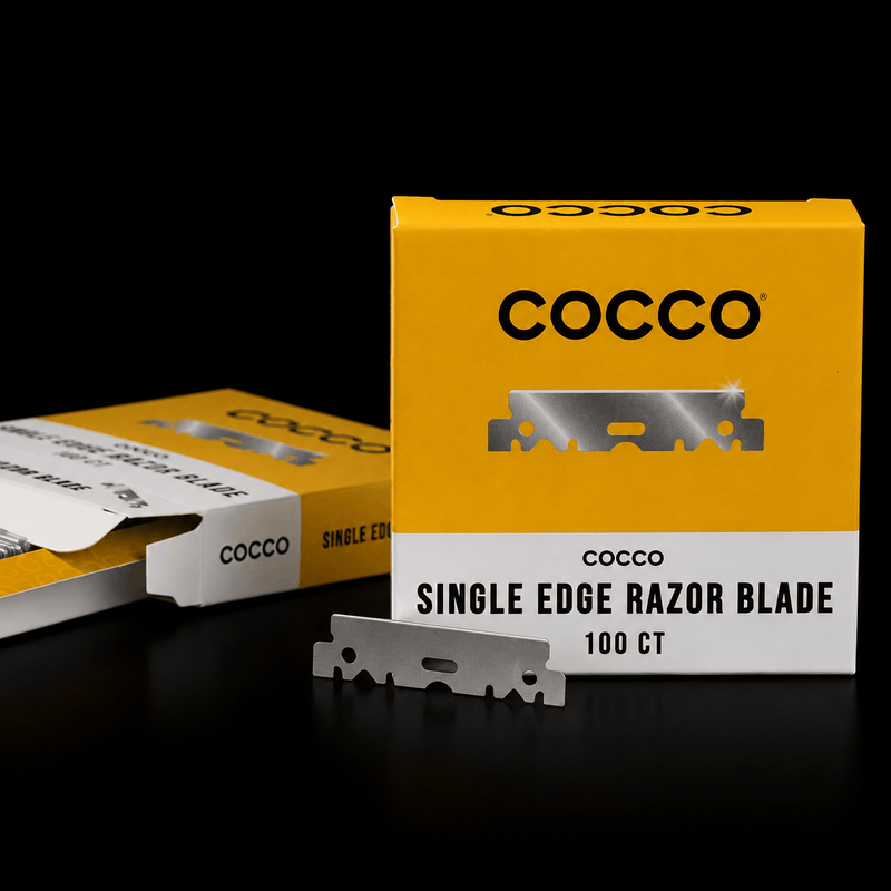 Cocco single edge razor blade box in yellow and white packaging with one silver razor blade displayed in front on a black background.