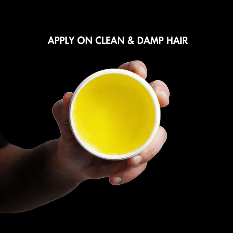 Hand holding the Rolda container with the open jar with text 'Apply on clean & damp hair' on a black background