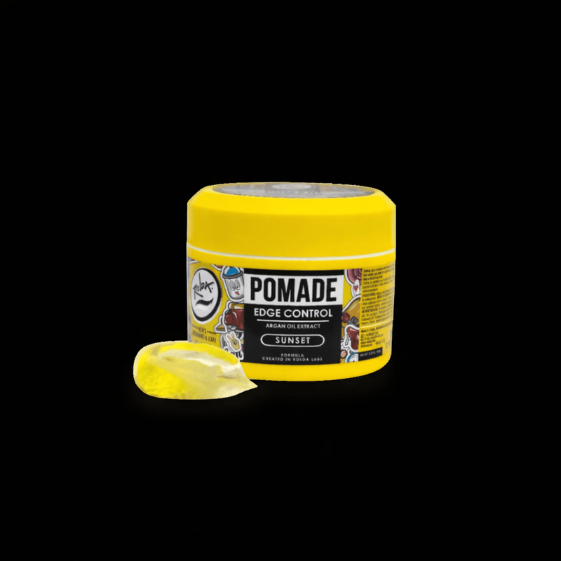 Yellow jar of pomade with a sample smear of pomade on a black background