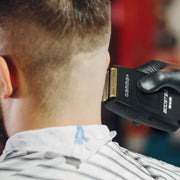 Person getting a haircut with a hair trimmer, focusing on the tool and the person's head.