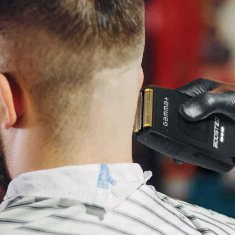 Person getting a haircut with a hair trimmer, focusing on the tool and the person's head.