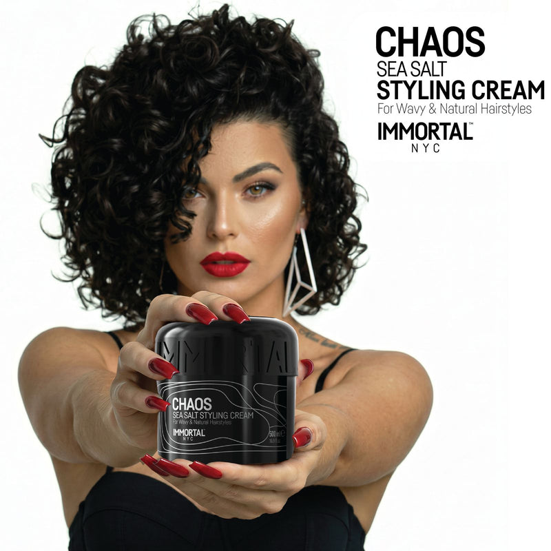 Woman with defined curls holding an open jar of Immortal NYC Chaos Sea Salt Curl Cream