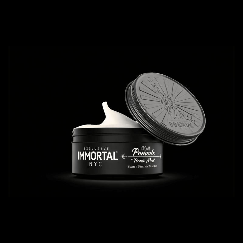 Open jar of Immortal NYC cream pomade with black lid on a black background