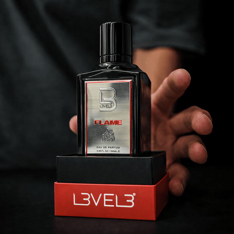 Bottle of Level 3 Flame perfume held by a hand with a black background