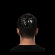 Person wearing two black velcro grips on the back of their head against a black background
