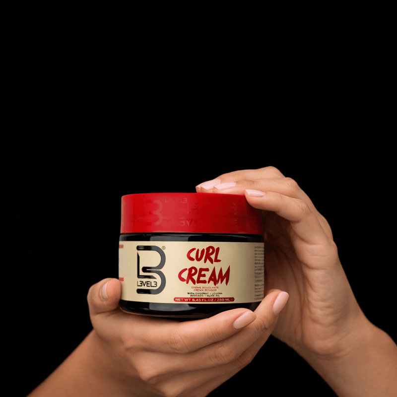 Jar of Level 3 Curl Cream held by a hand against a black background