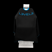 L3VEL3 Professional Rubber Neck Cutting Cape in black with blue trim, draped over a barber chair