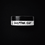 Jar of sculpting clay with a black lid on a black background