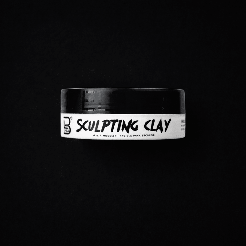 Jar of sculpting clay with a black lid on a black background