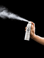 Hand holding a can of Mane & Tail hair product against a black background