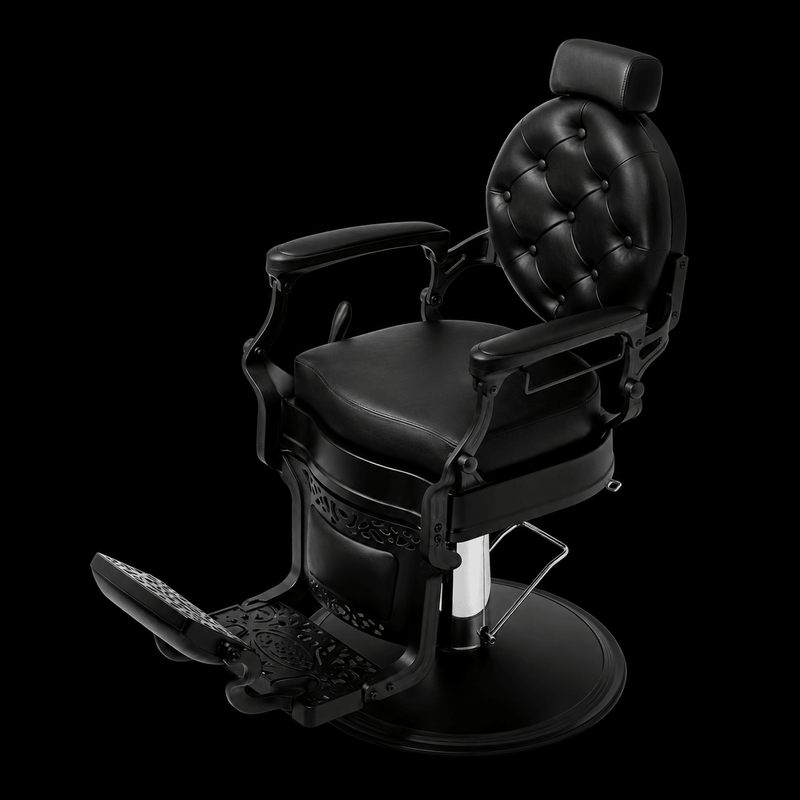 Primos Studio Barber Chair - all-black vintage barbershop chair with button-tufted backrest and filigree side panels, elevated angle