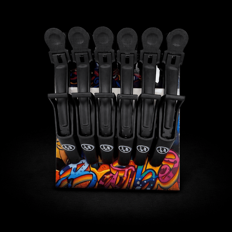 Set of black hair clips on a colorful display stand against a black background