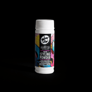 Hair styling powder bottle with colorful label on a black background. Primos Barber Supply