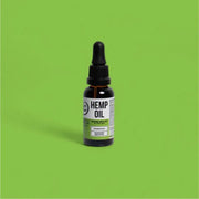 Bottle of hemp oil with a dropper on a green background
