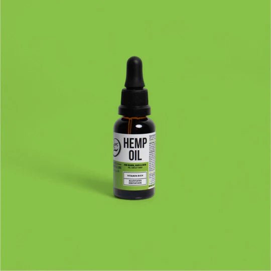 Bottle of hemp oil with a dropper on a green background