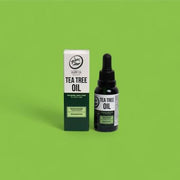 Tea tree oil bottle and packaging on a green background