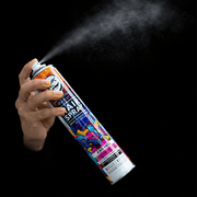 Hand holding a hair spray can with colorful label against a black background. Primos Barber Supply