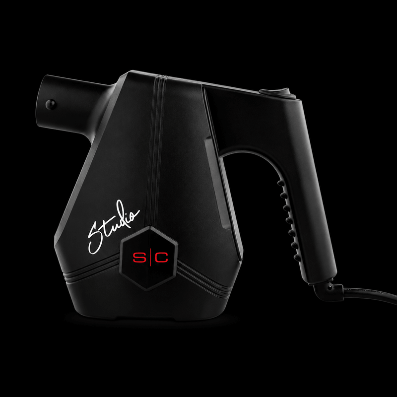 Black handheld steamer with 'Studio' branding on a black background