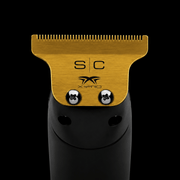 Hair trimmer head with gold top and black body on a black background