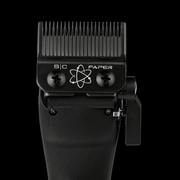 Black hair clipper with comb attachment on a black background