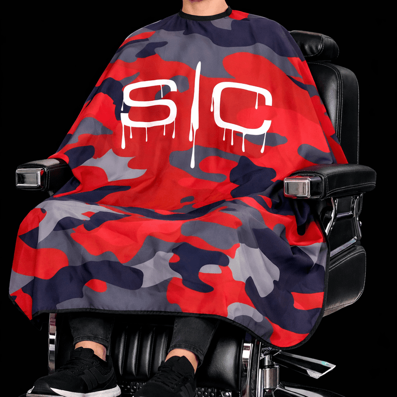 Person sitting in a chair with a red and gray camouflage cape draped over them.