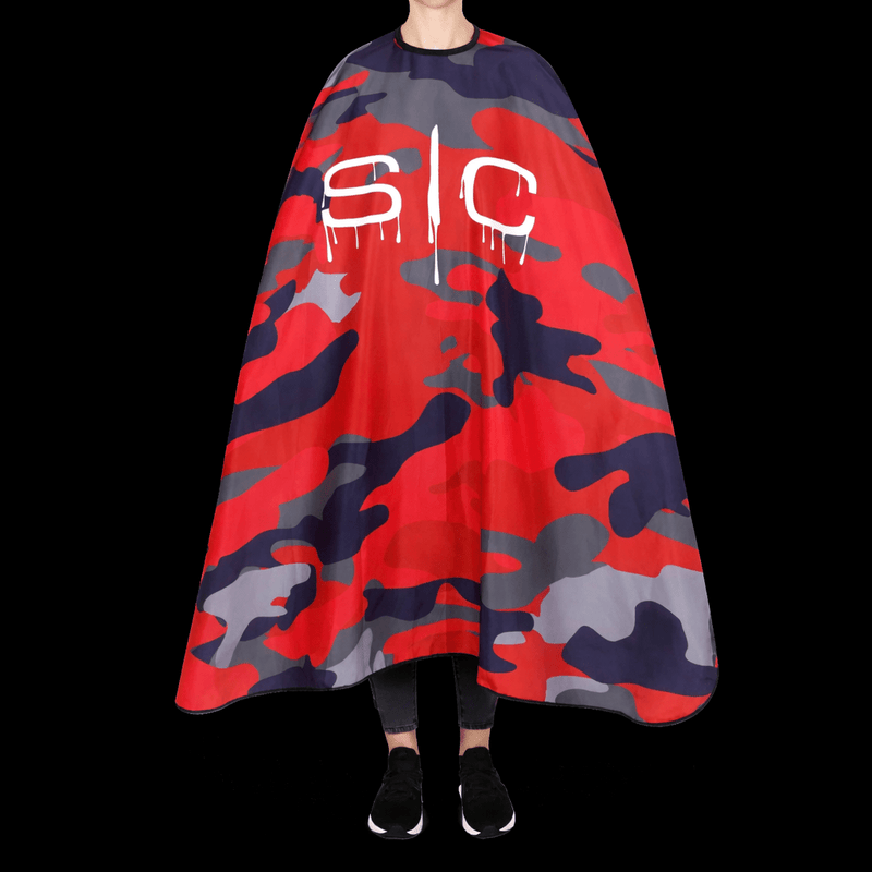 Person standing wearing a red and gray camouflage cape with 'SC' lettering on a black background