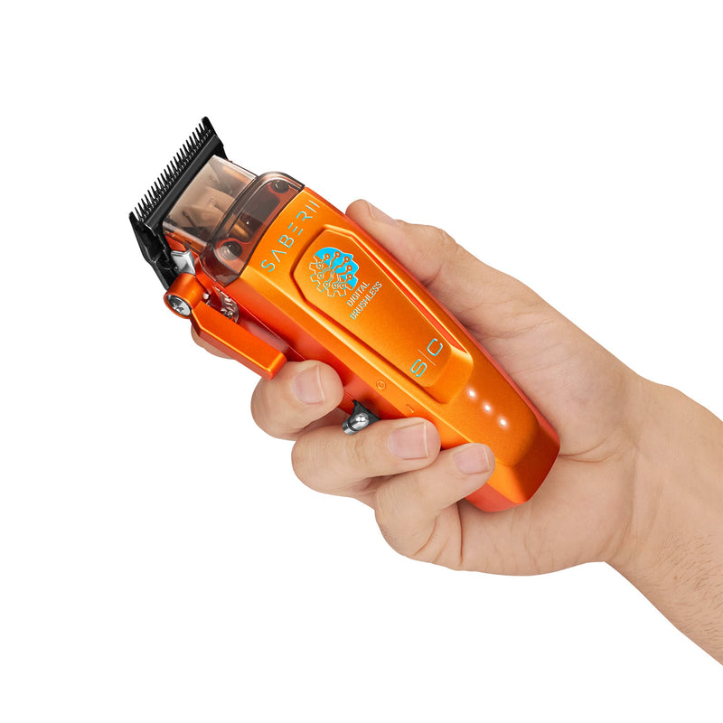 Hand holding the StyleCraft Saber 2.0 orange cordless clipper at an angle