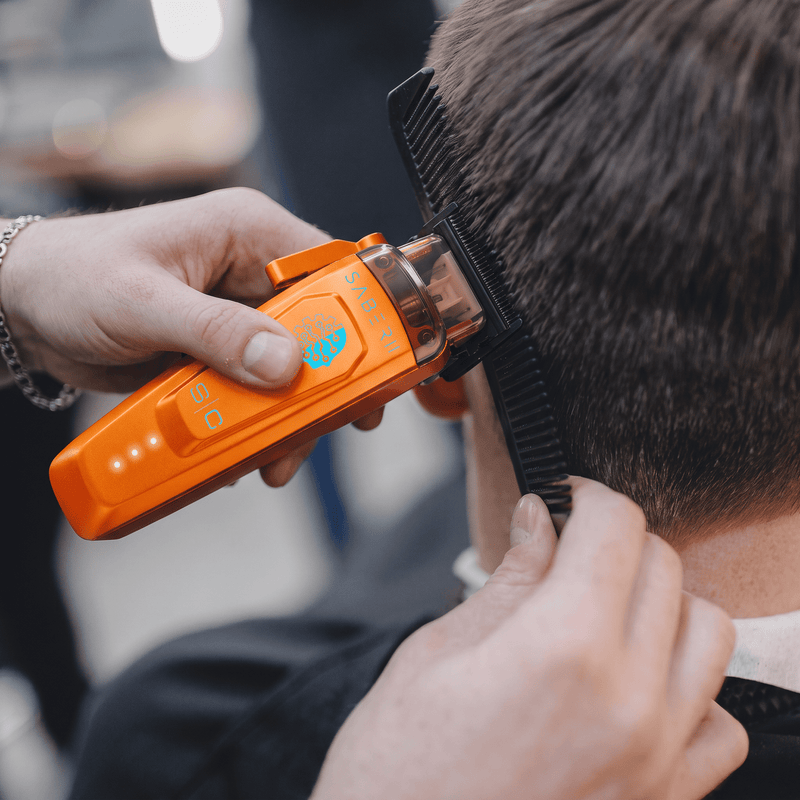 Barber doing clipper-over-comb on a client's side with the StyleCraft Saber 2.0 orange clipper