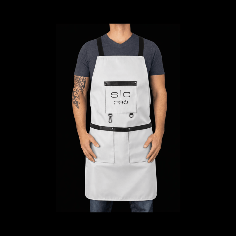 Person wearing a white apron with black accents on a black background