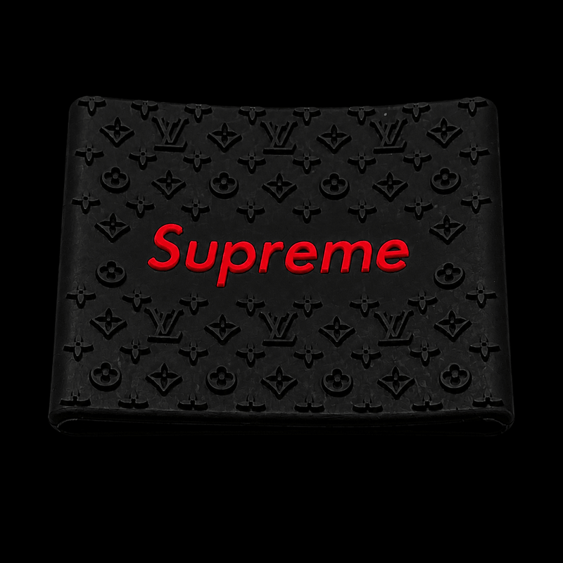 Black Supreme wallet with red logo and embossed monogram pattern on a black background.