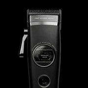 Black cordless hair clipper with silver metallic accents, featuring a circular brushed-metal motor cover and clipper blades, shown against a solid black background.